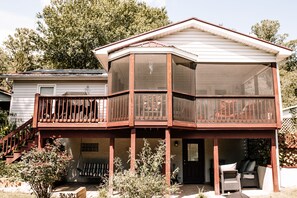 A two-story house with a covered porch, a screened balcony, and a front door.