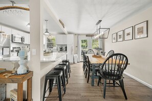 Una cocina amplia con una isla central, taburetes de bar y una mesa de comedor con sillas.