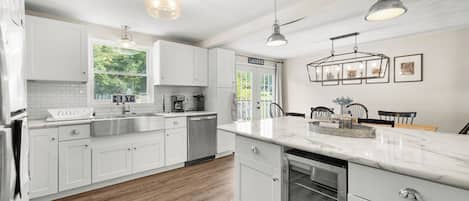 A modern kitchen with white cabinetry, a stainless steel sink, and a dishwasher.