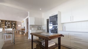 Una cocina moderna con armarios blancos, electrodomésticos de acero inoxidable y una mesa de madera.