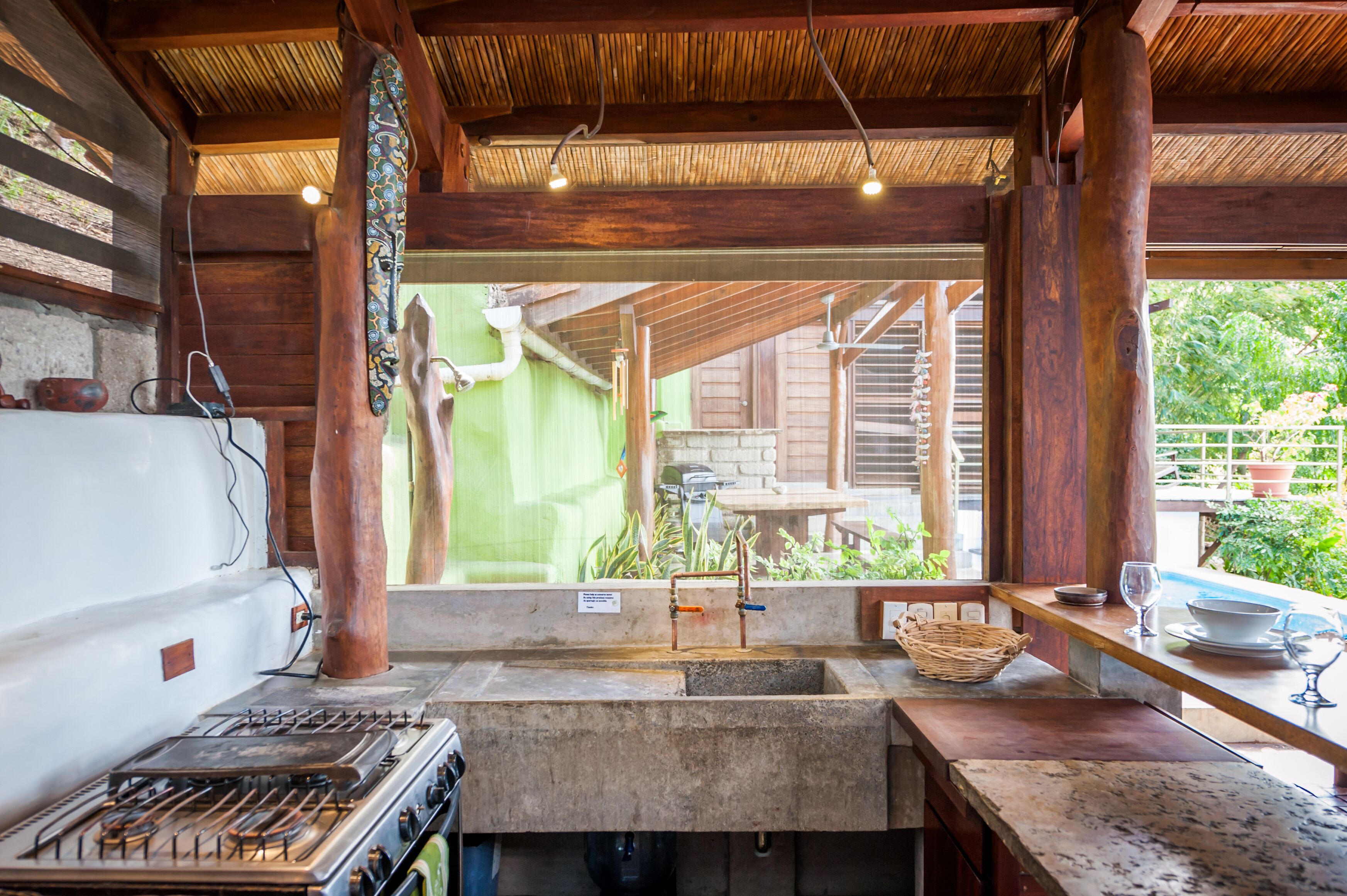 A kitchen with a gas stove, sink, and wooden beams.