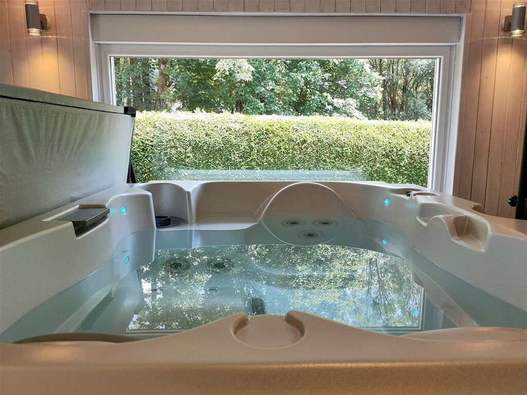 Un bain à remous avec vue sur une haie et des arbres à l’extérieur.