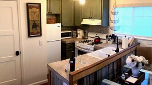 A kitchen with a central island, a stove, and a sink. There is a framed welcome sign on the wall and a hanging light fixture. - COZY condo located on Mill St. in downtown historic Grass Valley. (Grass Valley)