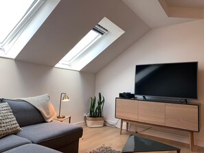 Relax in this inviting living space with a large flat-screen TV, comfortable sofa, and potted plant.