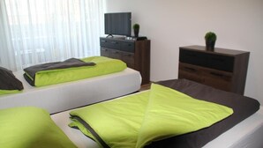 A hotel room with two beds, a TV on a dresser, and a small plant on the dresser. - Apartment with large terrace and free Wi-Fi (Eberstadt)