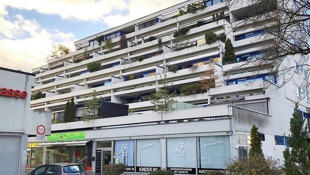 A multi-story building with balconies, a storefront with signage, and a parked car. - Apartment with large terrace and free Wi-Fi (Eberstadt)