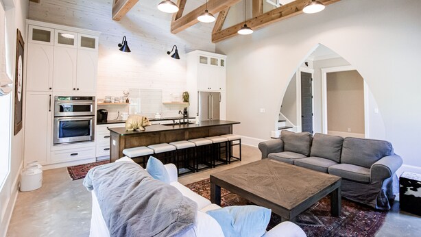 Eine moderne Küche mit integrierten Geräten, eine Essecke mit einer Bank und ein Wohnzimmer mit Sofa und Couchtisch.