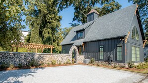 Ein modernes Haus mit einer Steinwand, einer Schotterauffahrt und einer Holzpergola.