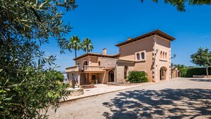 Une villa de style méditerranéen, dotée d’une façade en pierre, d’un balcon et d’une allée menant à l’entrée.