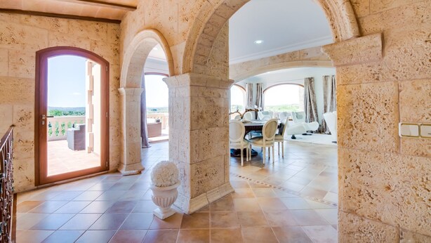 Une pièce spacieuse avec un plafond haut, des murs en pierre et un grand espace à manger aménagé avec des meubles modernes.