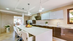 Une cuisine moderne dotée d’un îlot central, de meubles blancs et d’un éclairage suspendu.