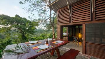 An outdoor dining area with a table set for four, overlooking a lush landscape.