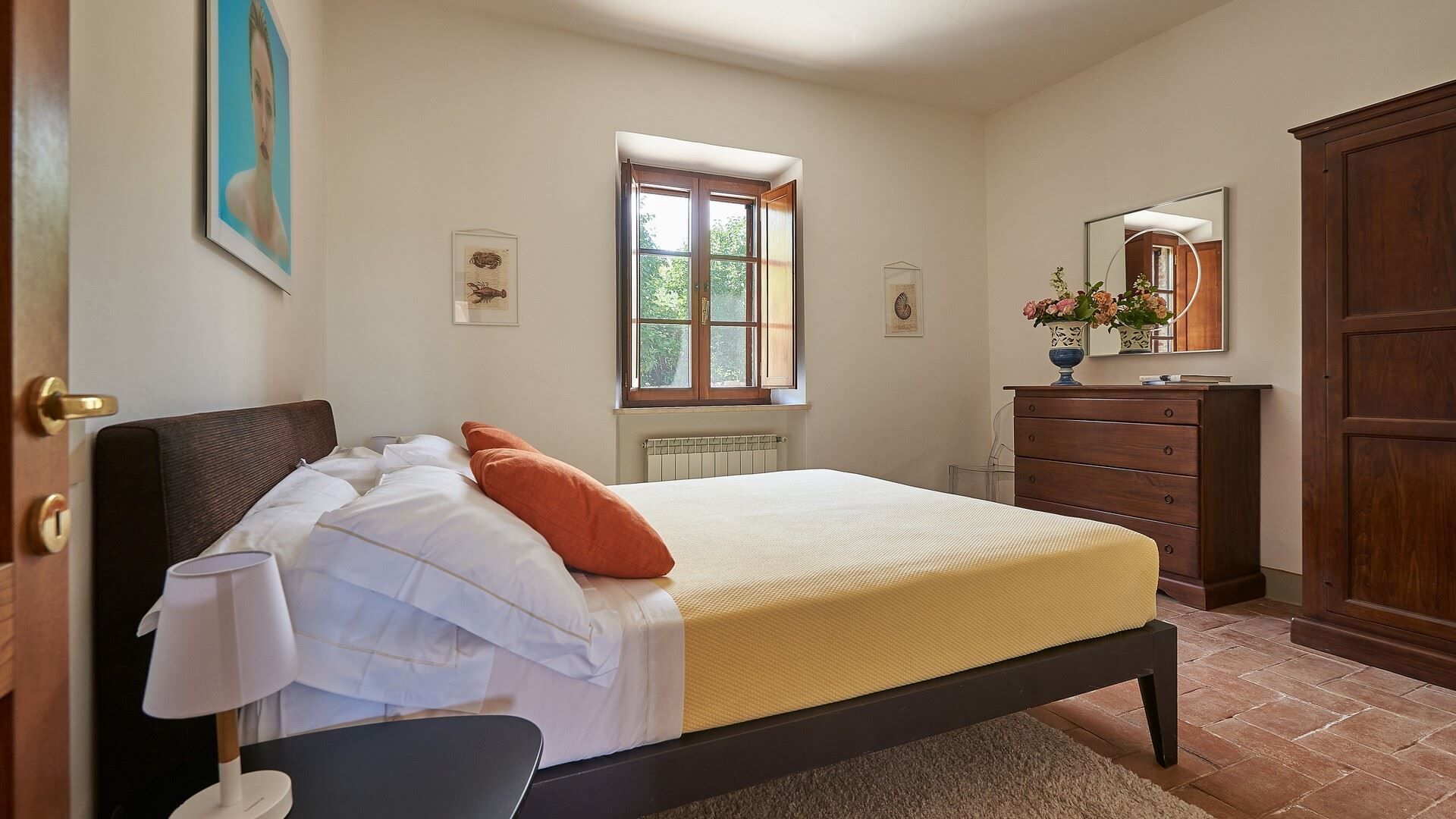 Ein Schlafzimmer mit einem Bett, einem Schminktisch, einem Fenster und einem Spiegel.