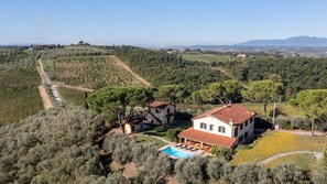 Une villa avec piscine, entourée d’oliveraies et de vignobles, offrant une vue sur les montagnes lointaines.