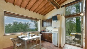 Una cocina acogedora con una mesa de comedor, sillas de mimbre y vistas al exterior.