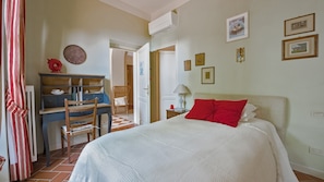 A bedroom with a bed, a desk, and a chair. There are pictures on the wall and an air conditioning unit above the desk. - Villetta, Punta Nera, Monte Argentario, Grosseto and Maremma (Monte Argentario)
