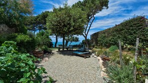 A garden with a gravel path, benches, and a view of the sea. - Villetta, Punta Nera, Monte Argentario, Grosseto and Maremma (Monte Argentario)