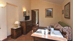 Ein Essbereich mit einem Holztisch, gedeckt für zwei Personen, einem Fernseher auf einer Kommode und gerahmten Kunstwerken an den Wänden.