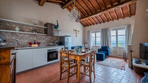 A spacious kitchen with a dining area, a chandelier, and a view through large windows. - Pesci, Montefiorile, Gaiole in Chianti, Siena and Chianti (Gaiole in Chianti)