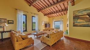A spacious living room with a high ceiling, large windows, and a painting on the wall. - Macia Viva, Castellina in Chianti, Siena and Chianti (Castellina in Chianti)