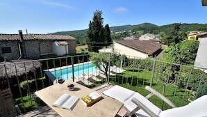En terrasse med swimmingpool, liggestole og en bog.