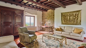 Un salon spacieux avec un plafond haut, un mur en pierre et une grande fenêtre donnant sur un paysage agréable.