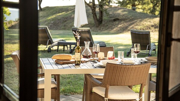 An outdoor dining area with wicker chairs and a table set for a meal, featuring wine glasses and a bottle. - Ciliegia, Poderone, Roccalbegna, Grosseto and Maremma (Roccalbegna)
