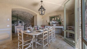 A dining area with a stone archway, a table set for four, and a view of the outside through a glass door. - Il Casetto, Radda in Chianti, Siena and Chianti (Radda in Chianti)