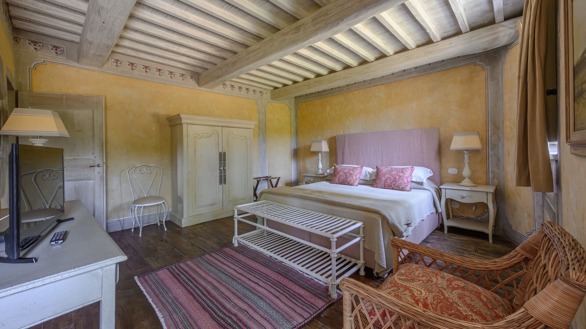 A bedroom with a bed, bedside tables, a chair, a desk, and a wardrobe.