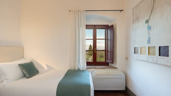 Una camera da letto con un letto, un termosifone, una finestra con tende e un quadro appeso al muro.