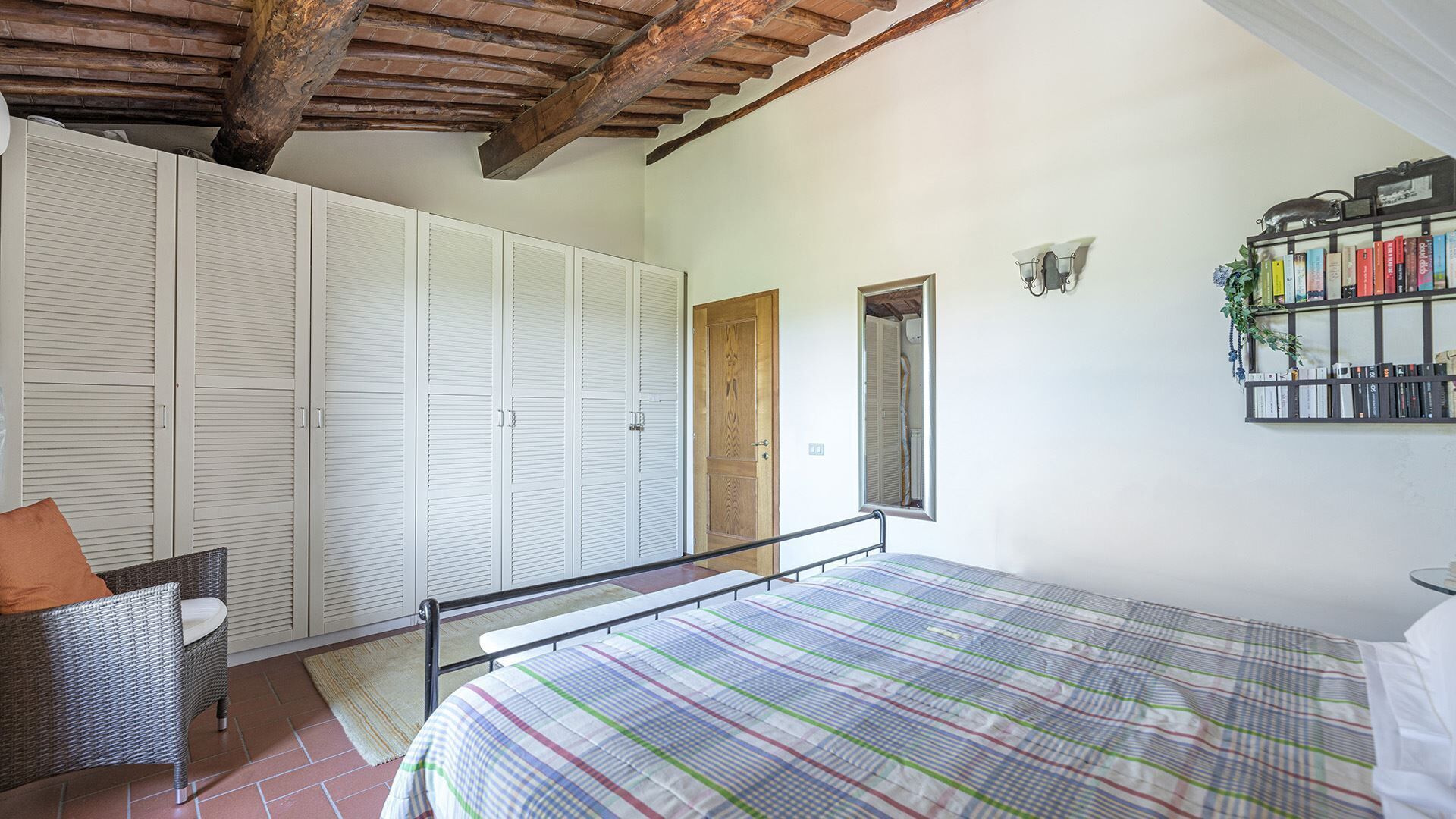 A bedroom with a bed, a wardrobe, a chair, and a bookshelf.