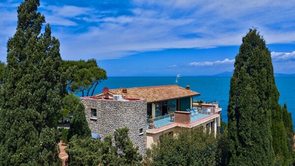A coastal house with a stone facade, a balcony with a pool, and a view of the sea. - Attico, Punta Nera, Monte Argentario, Grosseto and Maremma (Monte Argentario)