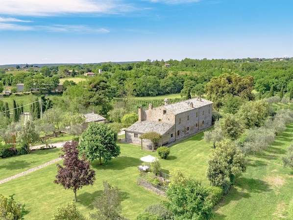 A stone building with a large lawn and surrounding trees.