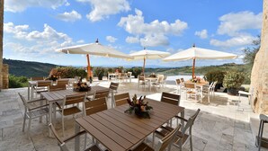 An outdoor patio with tables and chairs, surrounded by potted plants and umbrellas, overlooking a scenic landscape. - Anna, Fattoria la Pieve, Roccalbegna, Grosseto and Maremma (Roccalbegna)