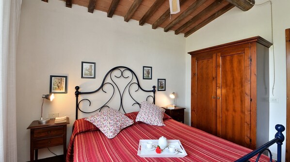 Un dormitorio con cama, armario de madera, mesitas de noche y cuadros enmarcados en la pared.