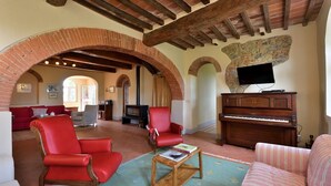 Un salón amplio con chimenea, un piano y asientos cómodos.