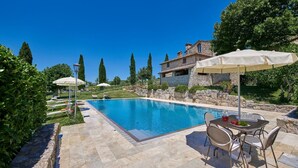A swimming pool with lounge chairs and umbrellas, a stone building, and a stone wall in the background. - Borratella, Gaiole in Chianti, Siena and Chianti (Gaiole in Chianti)