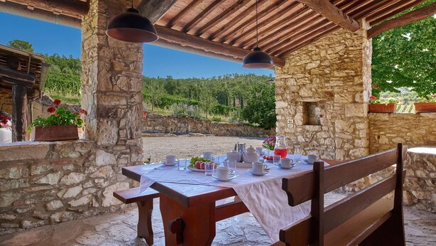 An outdoor dining area with stone walls, wooden benches, and hanging pendant lights. - Borratella, Gaiole in Chianti, Siena and Chianti (Gaiole in Chianti)