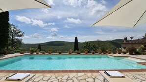 A pool with lounge chairs and umbrellas, surrounded by potted plants and a view of hills. - Il Poggetto a Vescinino, Radda in Chianti, Siena and Chianti (Radda in Chianti)