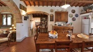 A rustic kitchen with wooden beams, a tiled floor, and a dining area with a wooden table and chairs. - Il Poggetto a Vescinino, Radda in Chianti, Siena and Chianti (Radda in Chianti)