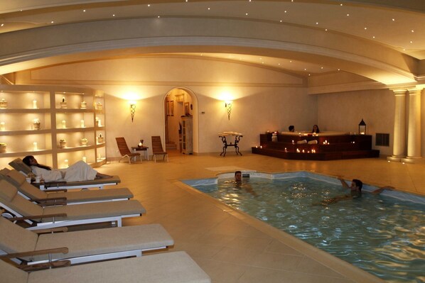 Un'area benessere con piscina, lettini e una reception.