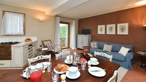 Ein Essbereich mit einem Holztisch, gedeckt für ein Frühstück, einem blauen Sofa und einer Küche mit weißen Schränken.