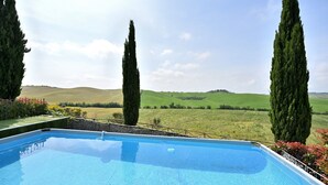 Une piscine offrant une vue sur des collines verdoyantes et de grands arbres.