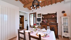 Une salle à manger avec une table en bois dressée pour le repas, un buffet en bois agrémenté d’objets décoratifs et un meuble blanc aux portes vitrées.