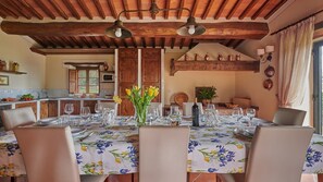 Zona pranzo con tavolo apparecchiato per sei, circondato da sedie in legno.
