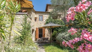 Un bâtiment en pierre doté d’un patio aménagé avec du mobilier d’extérieur et une table.