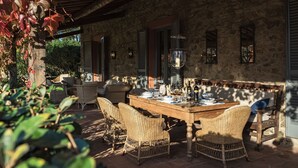 An outdoor dining area with wicker furniture and a stone wall backdrop.