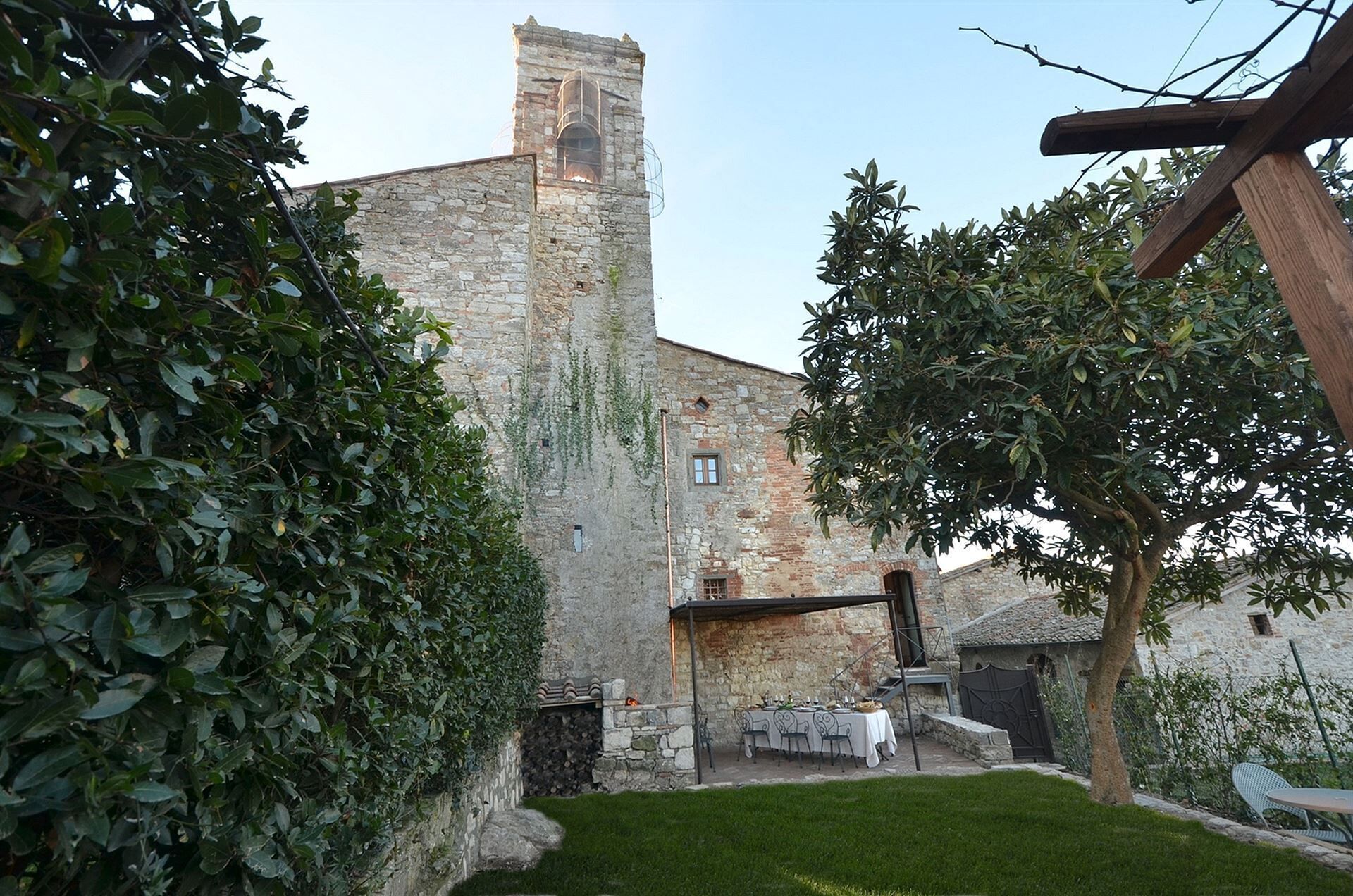 Ein Innenhof mit einem Steinhaus, einer Rasenfläche und einem Essplatz.