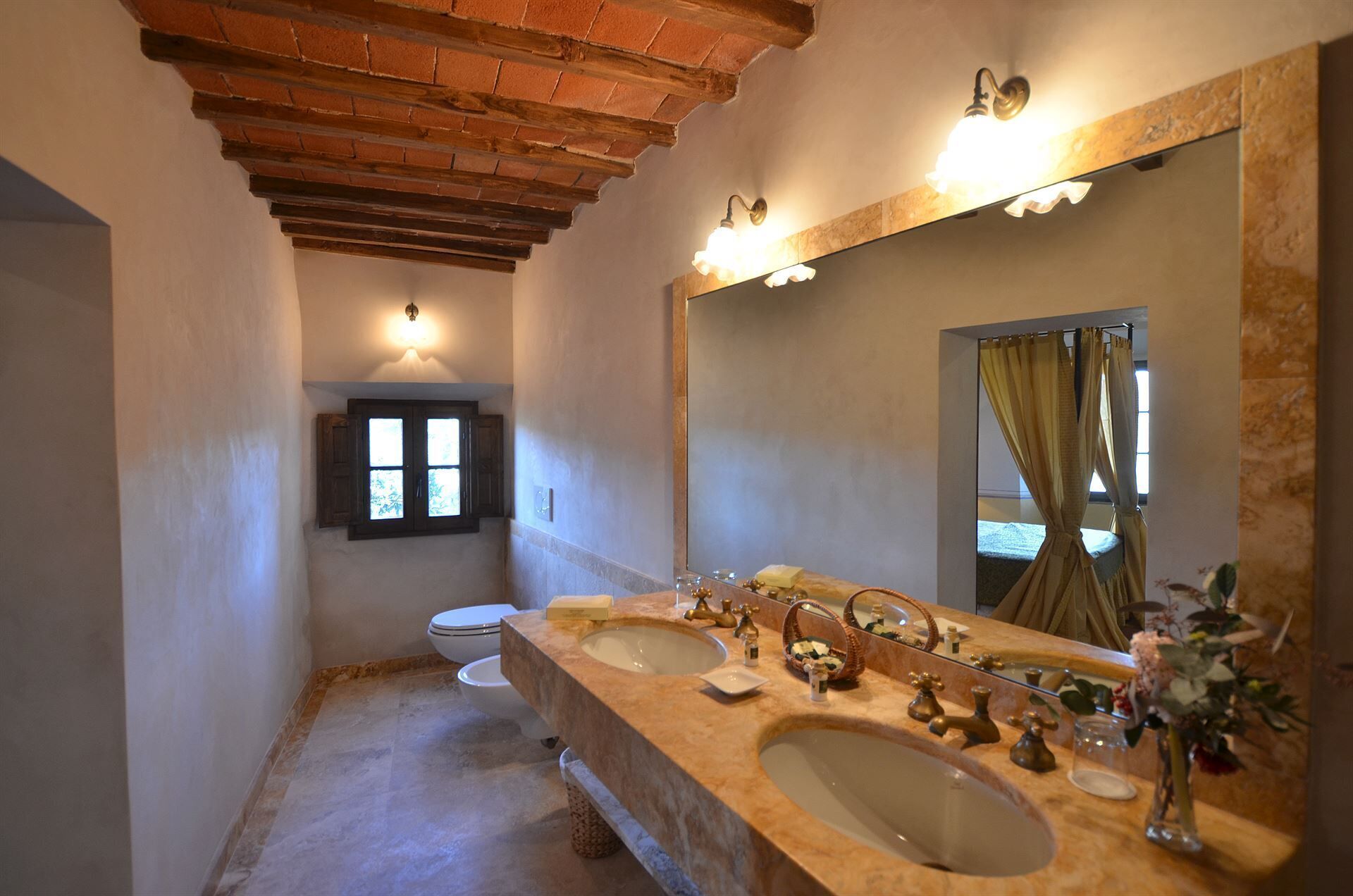 A bathroom with a large mirror, two sinks, and a toilet.