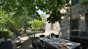 An outdoor dining area with a stone building backdrop, tables set with plates and wine glasses, and a rustic ambiance. - Villa Beba, Castellina in Chianti, Siena and Chianti (Castellina in Chianti)